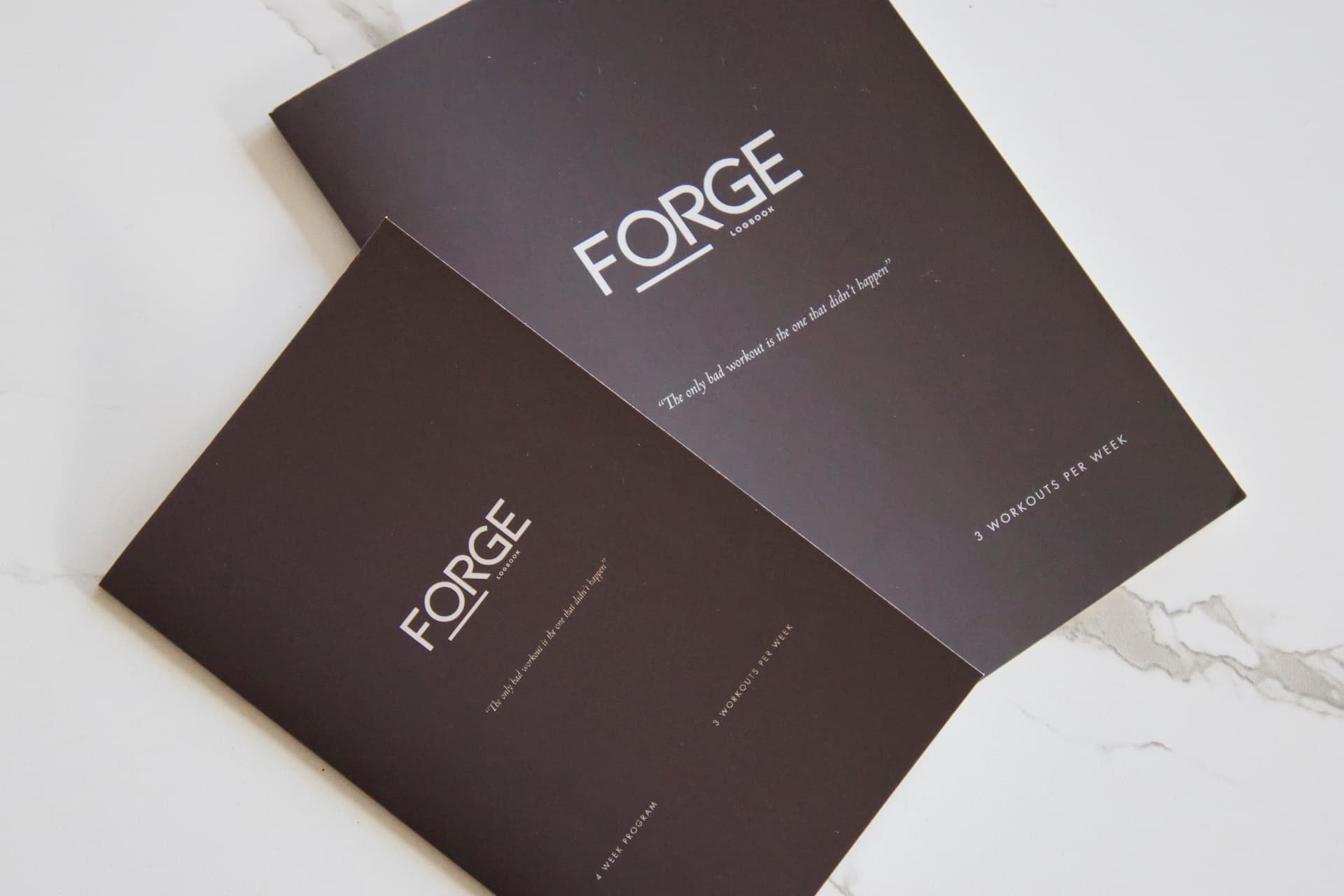 Athlete reviewing a ForgeLogbooks training journal between sets